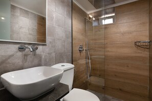 A modern bathroom with a freestanding bathtub, a toilet, and a walk-in shower with wooden paneling. - Lindos Citrin Suites (Rhodes)