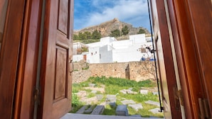 A wooden door opening to a courtyard with stone steps and white buildings in the background. - Lindos Citrin Suites (Rhodes)