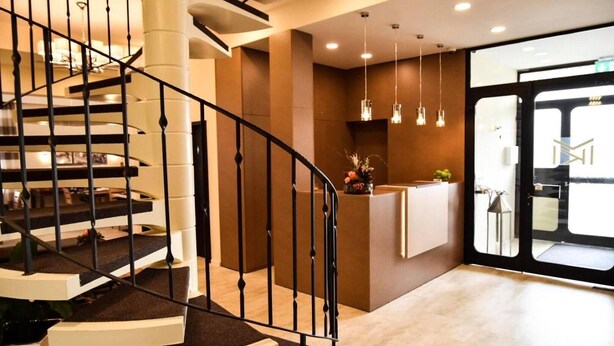 A modern hotel lobby with a spiral staircase, a reception desk, and pendant lighting.