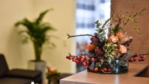 A reception area with a wooden reception desk, a potted plant, and a decorative floral arrangement.