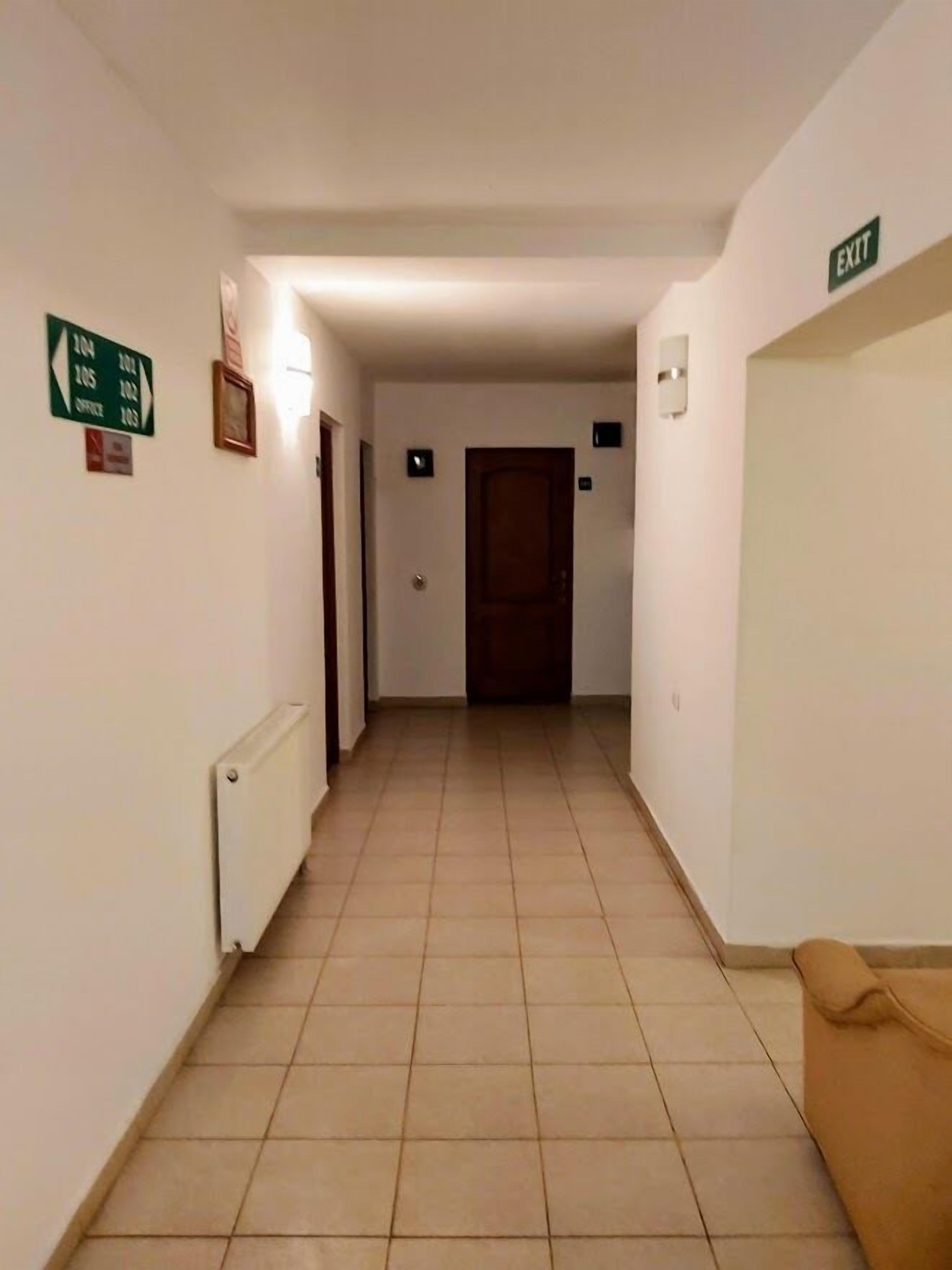 A hallway with a sign indicating office locations, a radiator, and an exit sign.