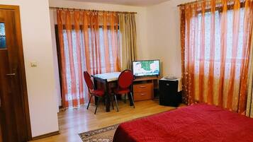 A room with a bed, a desk with a computer, a chair, and a television.