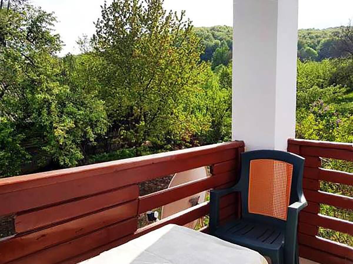 A balcony with a wooden railing, a plastic chair, and a table.