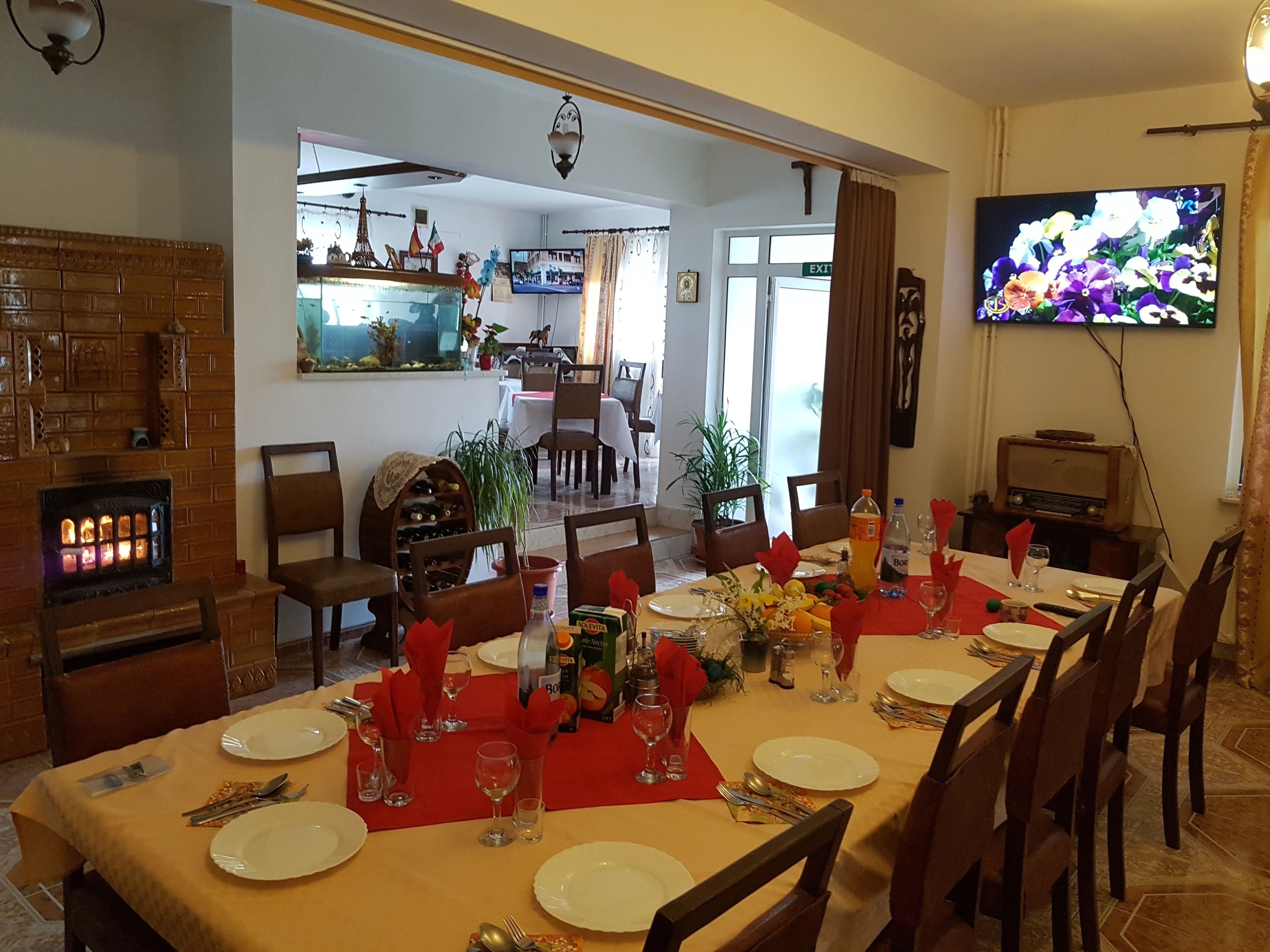 A dining area with a long table set for a meal, a fireplace, and a television on the wall.
