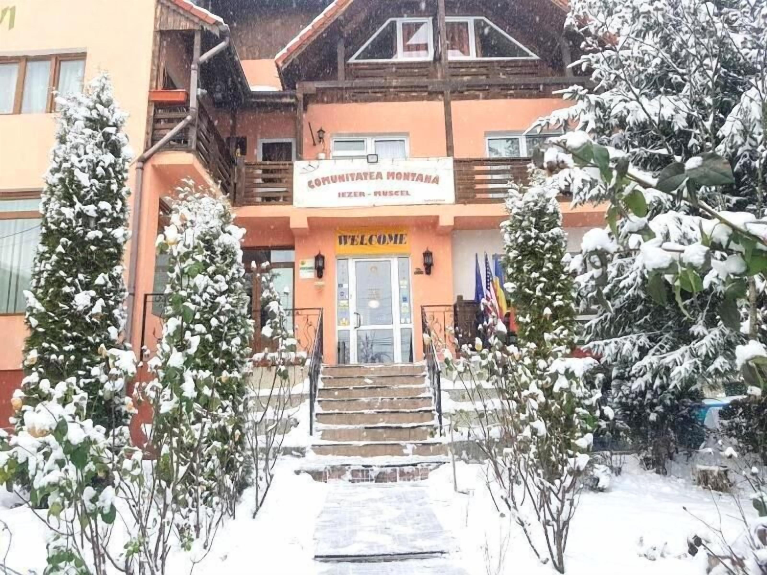 A building with a sign reading "COMMUNITAETA MONTANA" and a "WELCOME" sign at the entrance.