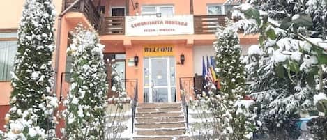 A building with a sign reading "COMMUNITAETA MONTANA" and a "WELCOME" sign at the entrance.