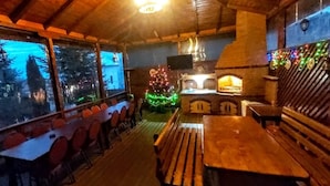 A cozy restaurant with a wooden interior, a Christmas tree, and a fireplace. - Pensiunea Agroturistica Piscul Soarelui (Godeni)