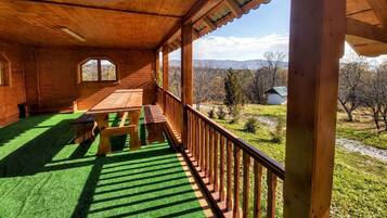 Una cabaña de madera con balcón, una mesa de madera y un banco.