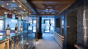 A corridor with a glass display case of various bottles, a wooden bench, and a stone wall. - Boutique Hotel die Mittagspitze Superior (Damüls)