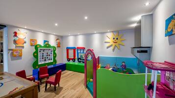 Children can play and learn in this vibrant room with a playpen, table, and colorful play structures.