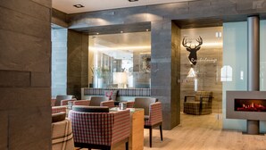 A lobby with checkered chairs, a fireplace, and a deer head logo. - Boutique Hotel die Mittagspitze Superior (Damüls)