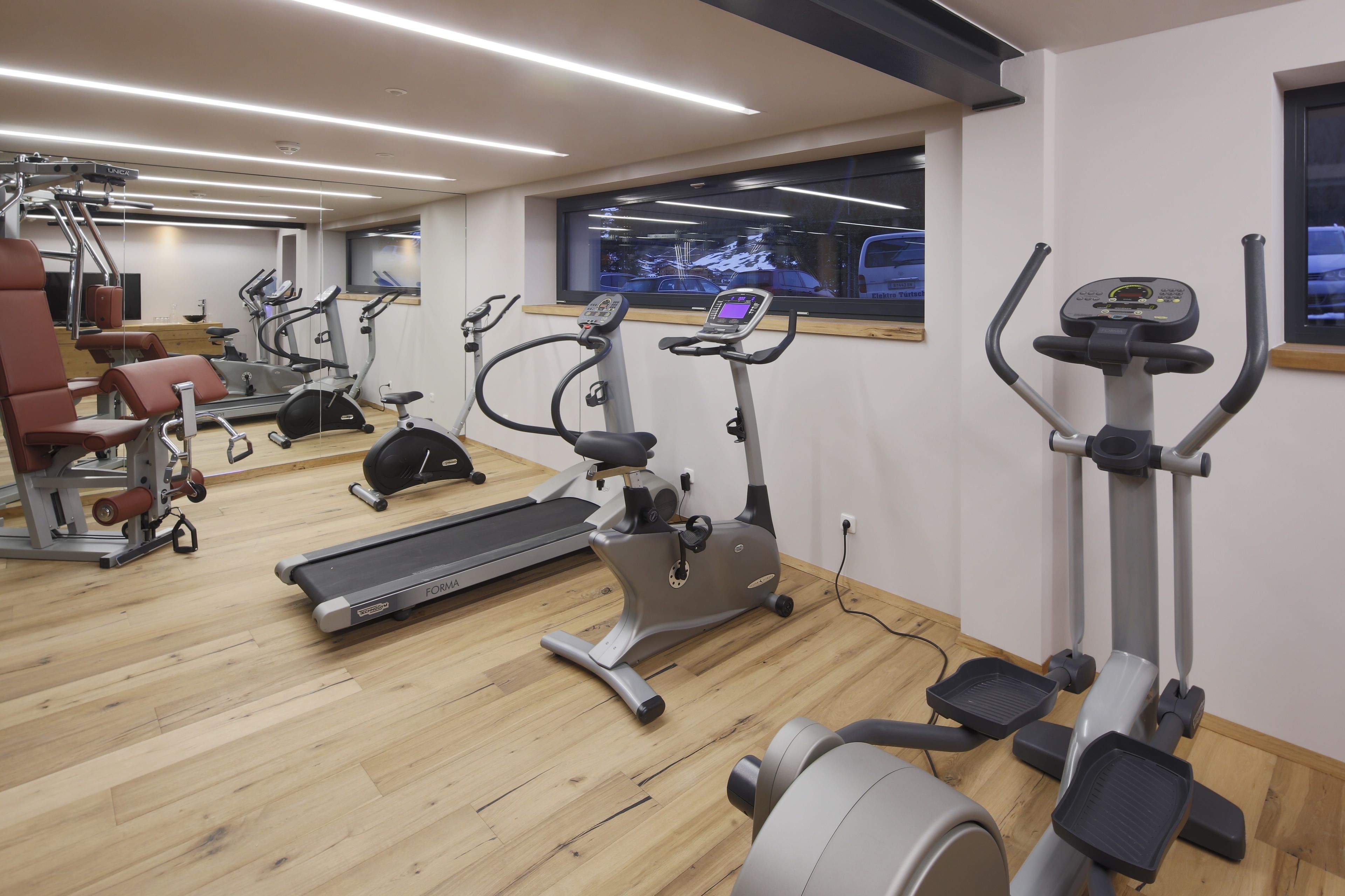 Een sportschool met diverse fitnessapparaten, waaronder loopbanden, elliptische trainers en krachtapparaten.