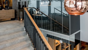 A modern interior with a staircase, glass walls, and metallic spherical light fixtures. - Boutique Hotel die Mittagspitze Superior (Damüls)