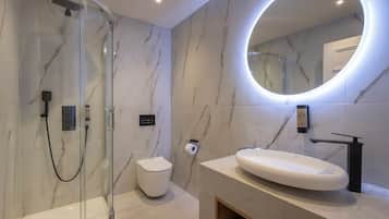 A modern bathroom with a glass-enclosed shower, a white toilet, and a large oval sink with a black faucet.