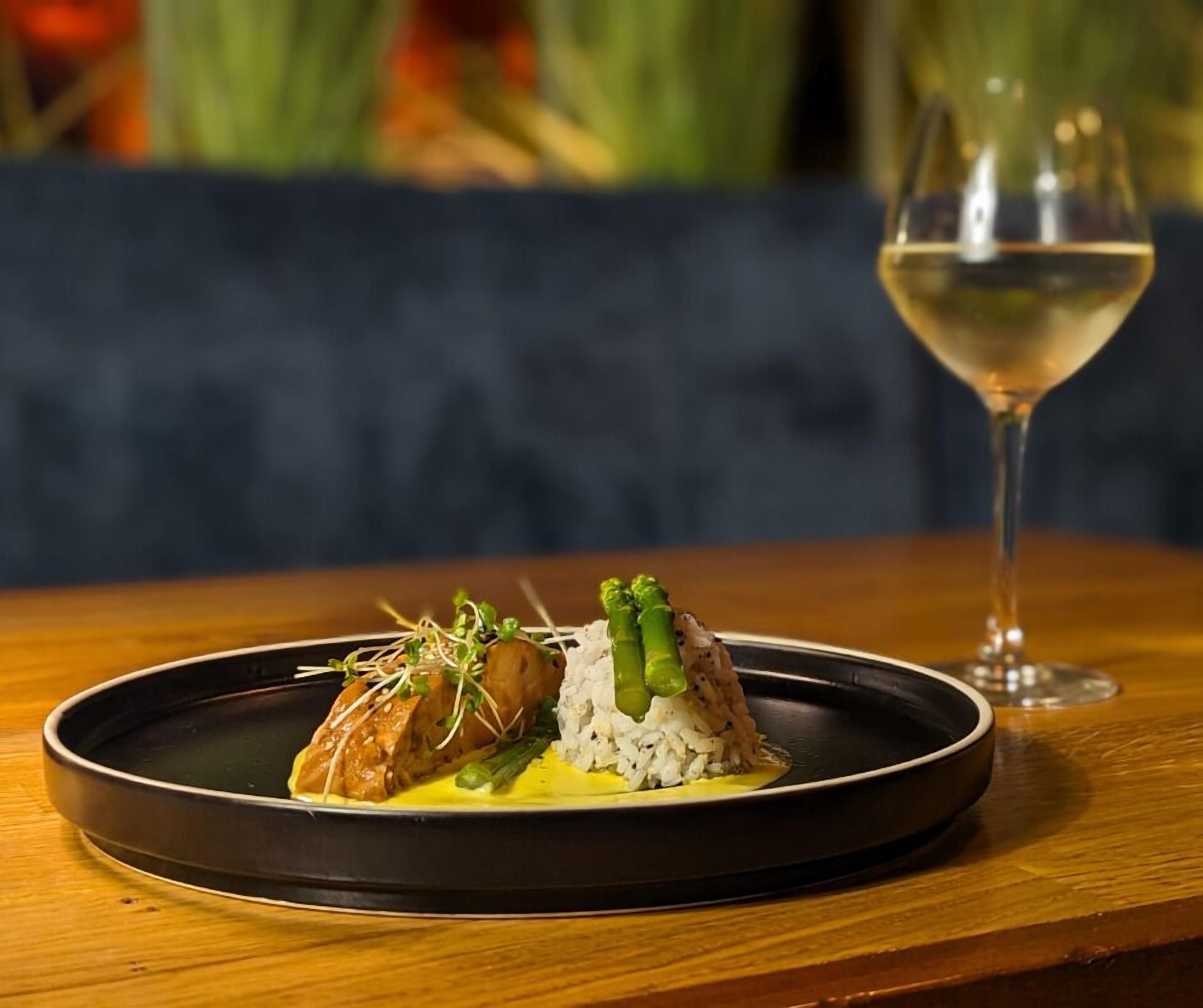 A plate of food with a glass of white wine on a wooden table.