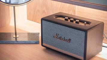 A Marshall amplifier on a wooden surface with a modern lamp in the background.