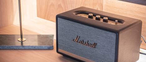 Un amplificador Marshall sobre una superficie de madera, con una lámpara moderna al fondo.