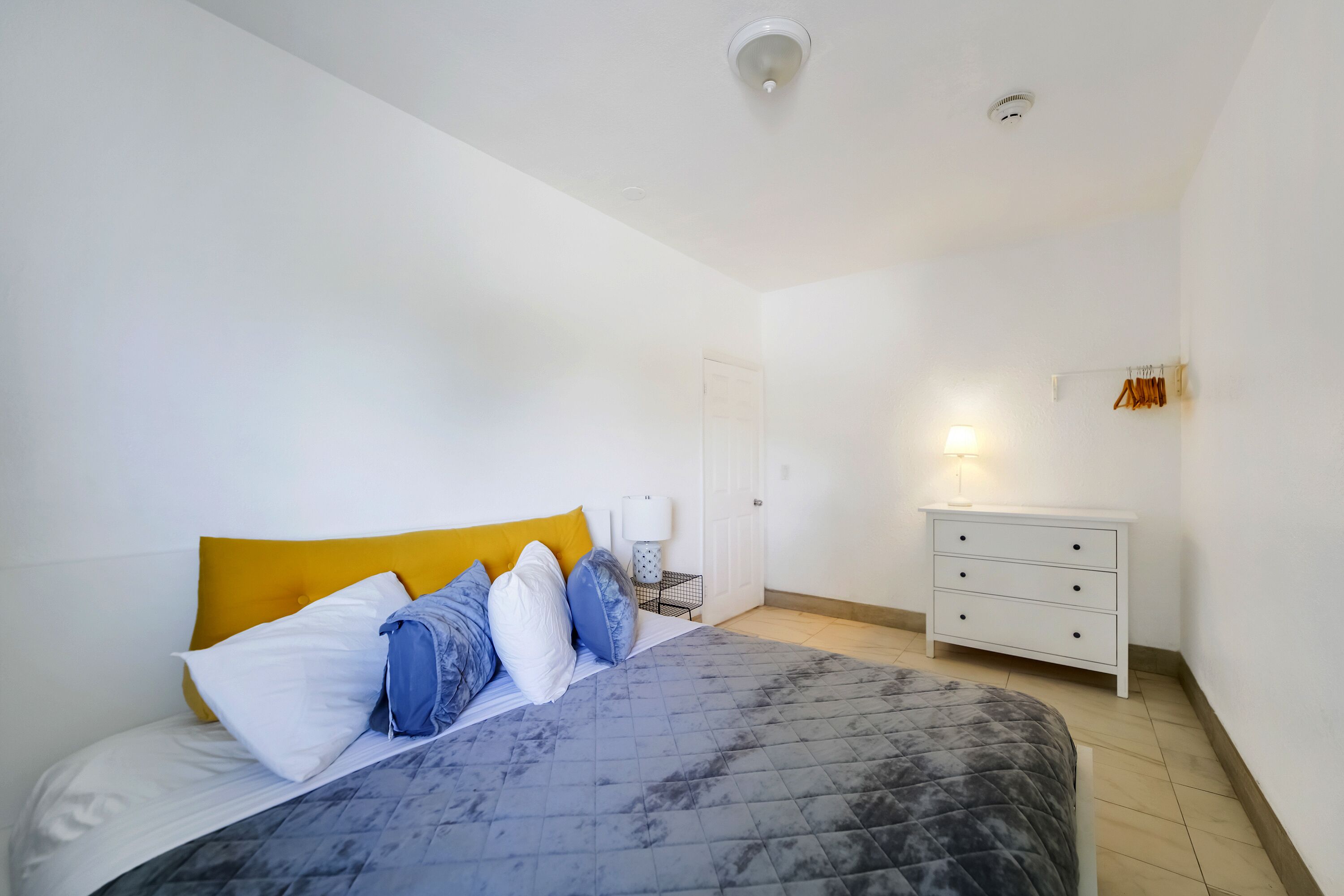Une chambre à coucher avec un lit, une table de chevet, une commode et une porte.