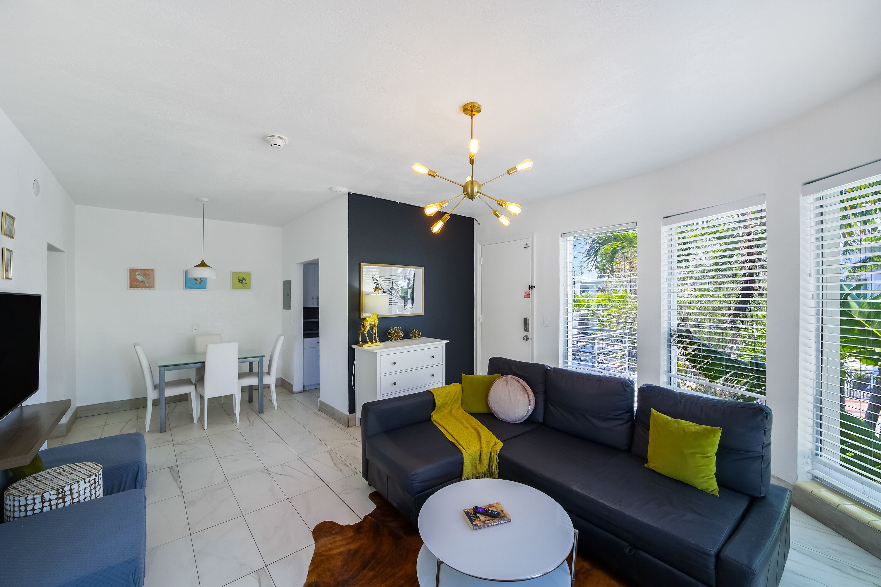 A modern living room with a sofa, coffee table, and dining area.