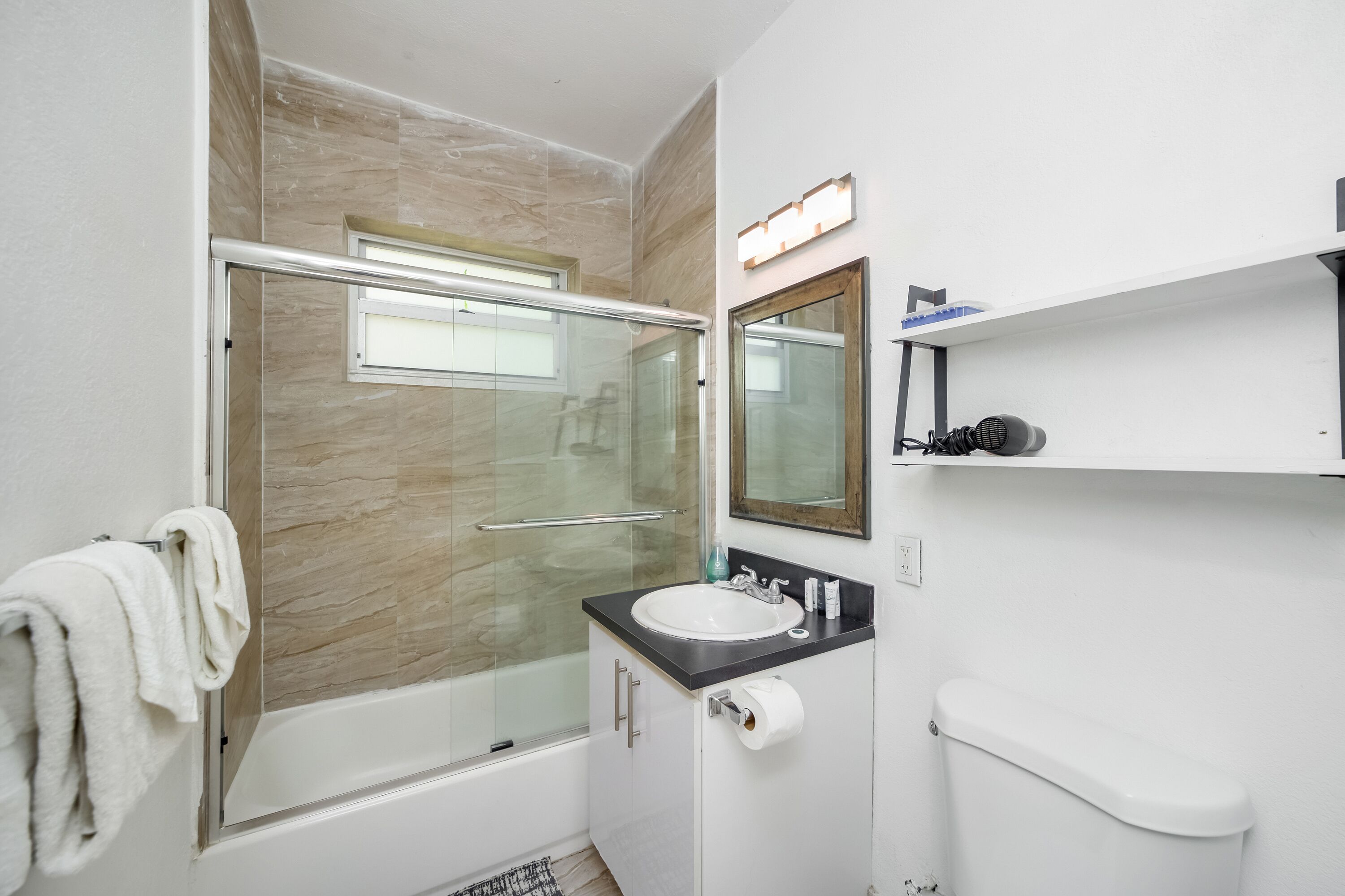 A bathroom with a glass-enclosed shower, a sink with a mirror, and a toilet.