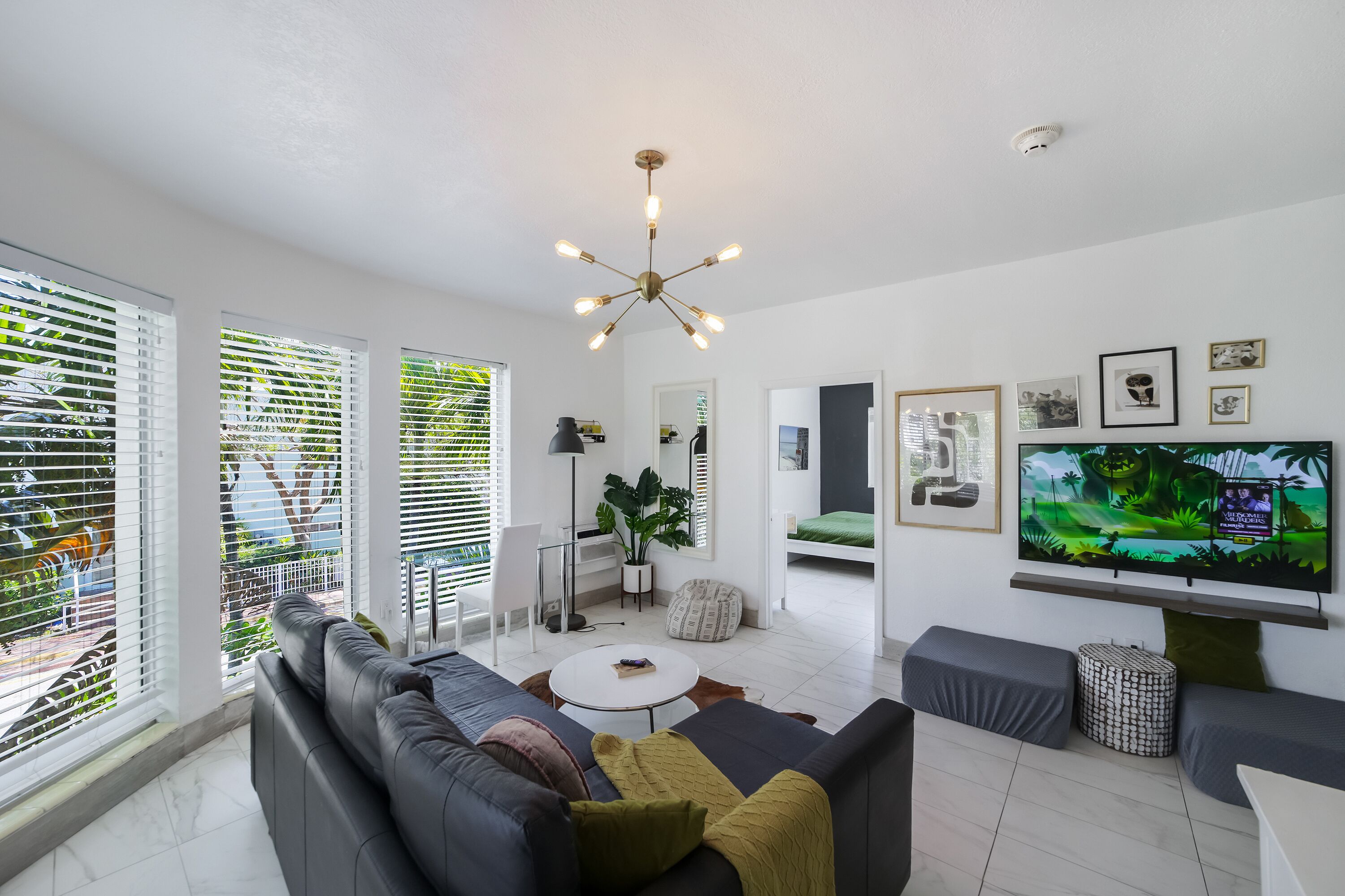 Ein modernes Wohnzimmer mit einer Couch, einem Couchtisch, einem Fernseher und einer Pflanze.