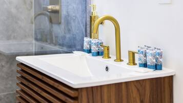 A bathroom with a white sink, gold faucets, and wooden slats.