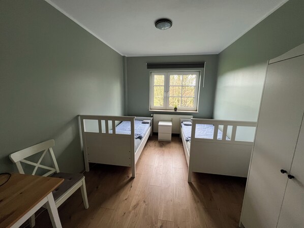 A room with two single beds, a desk, a chair, and a window with a view of trees. - Bett4you Peiner Hof (Prisdorf)