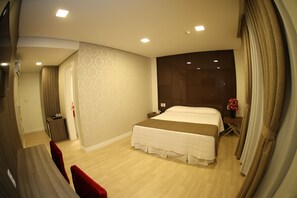 Una habitación de hotel moderna con una cama grande, una mesita de noche y un pequeño escritorio.