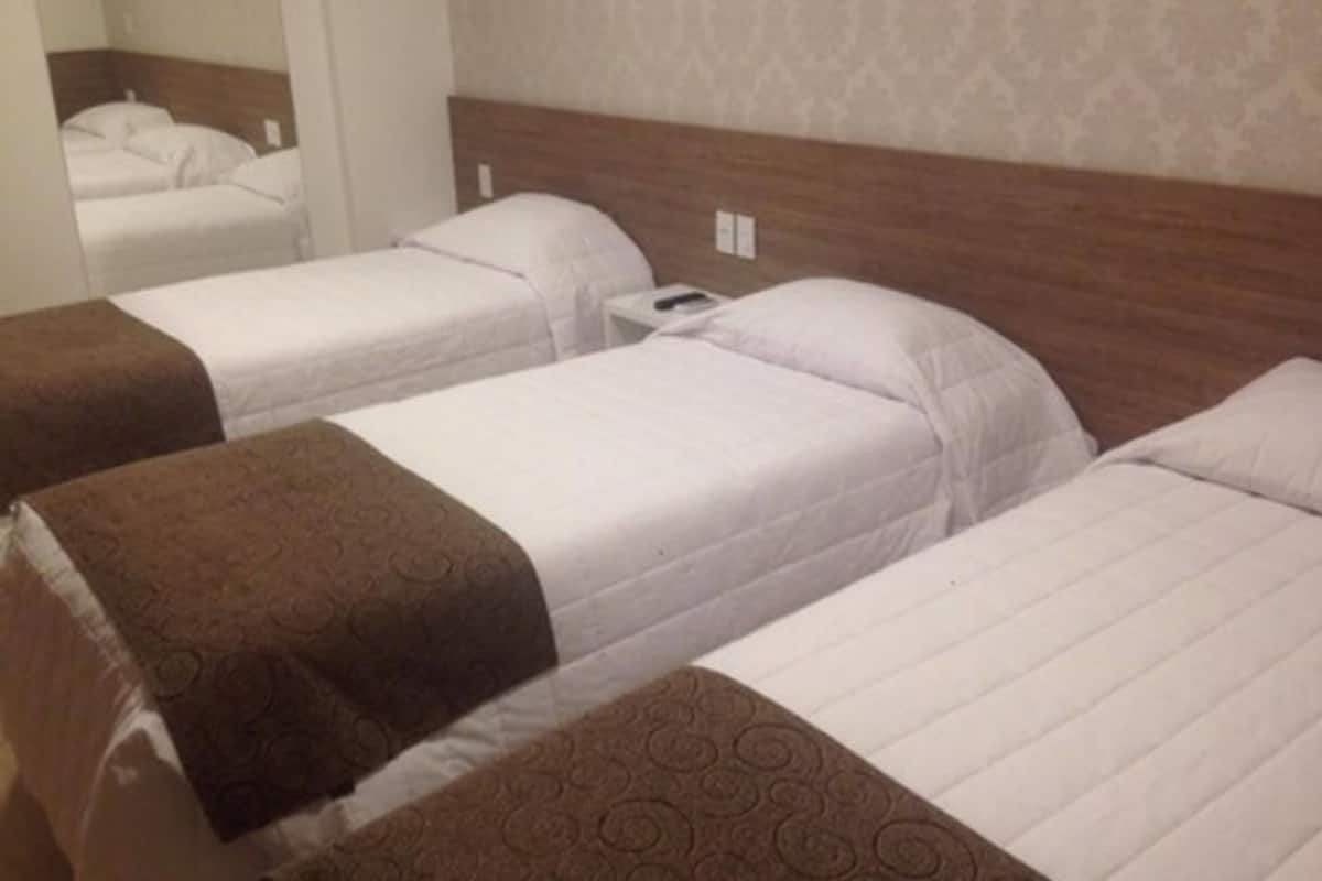 Ein Hotelzimmer mit zwei Einzelbetten, jeweils mit brauner Kopfteil und weißer Bettwäsche.