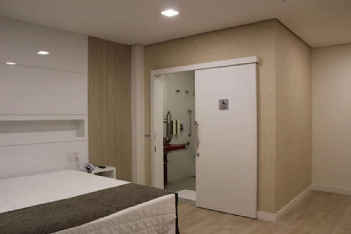 Ein Schlafzimmer mit Bett, Nachttisch, Kleiderschrank und einem durchgegangenen Tür sichtbaren Badezimmer.