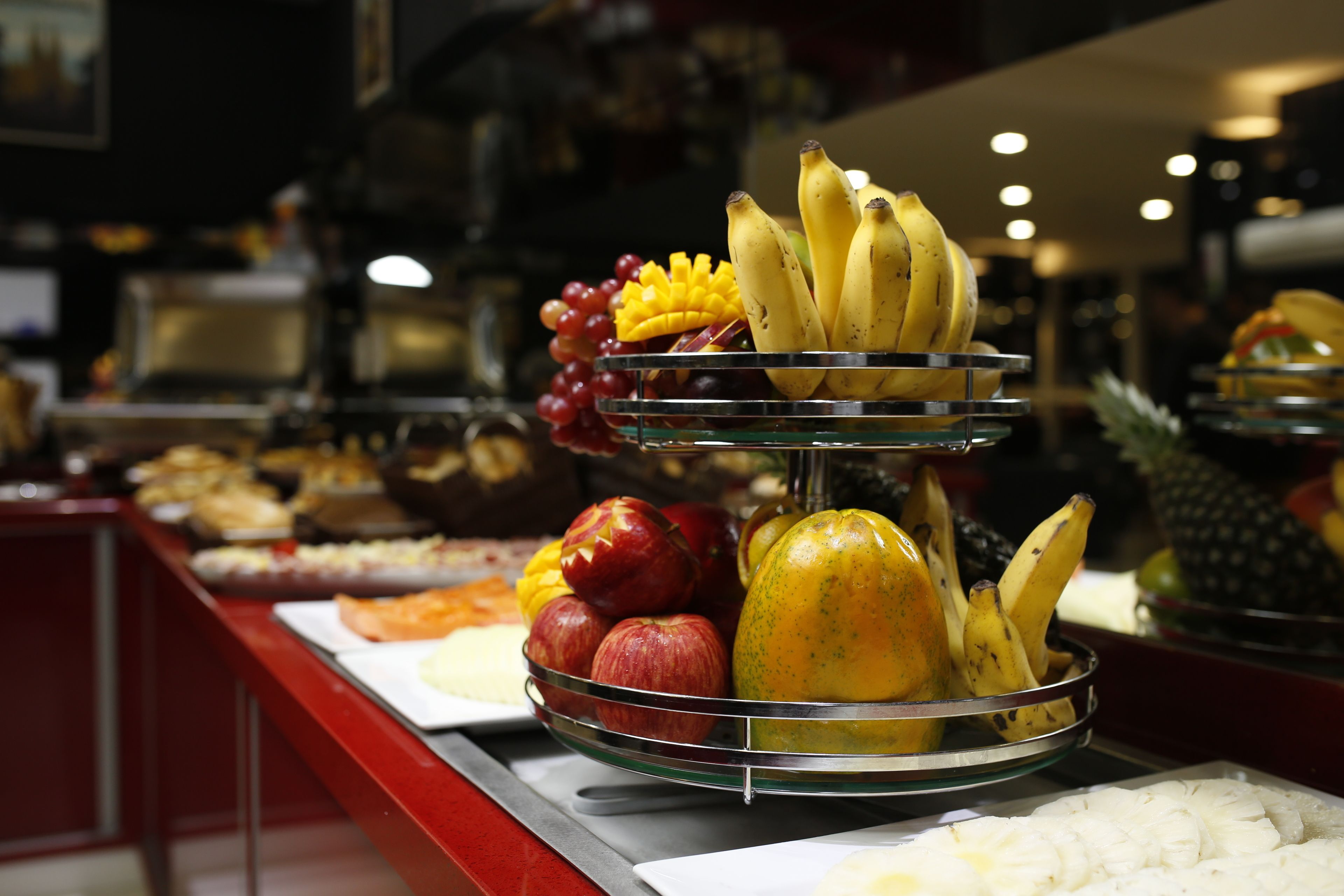 Un bufé con diversas frutas y verduras dispuestas sobre un soporte de vidrio.