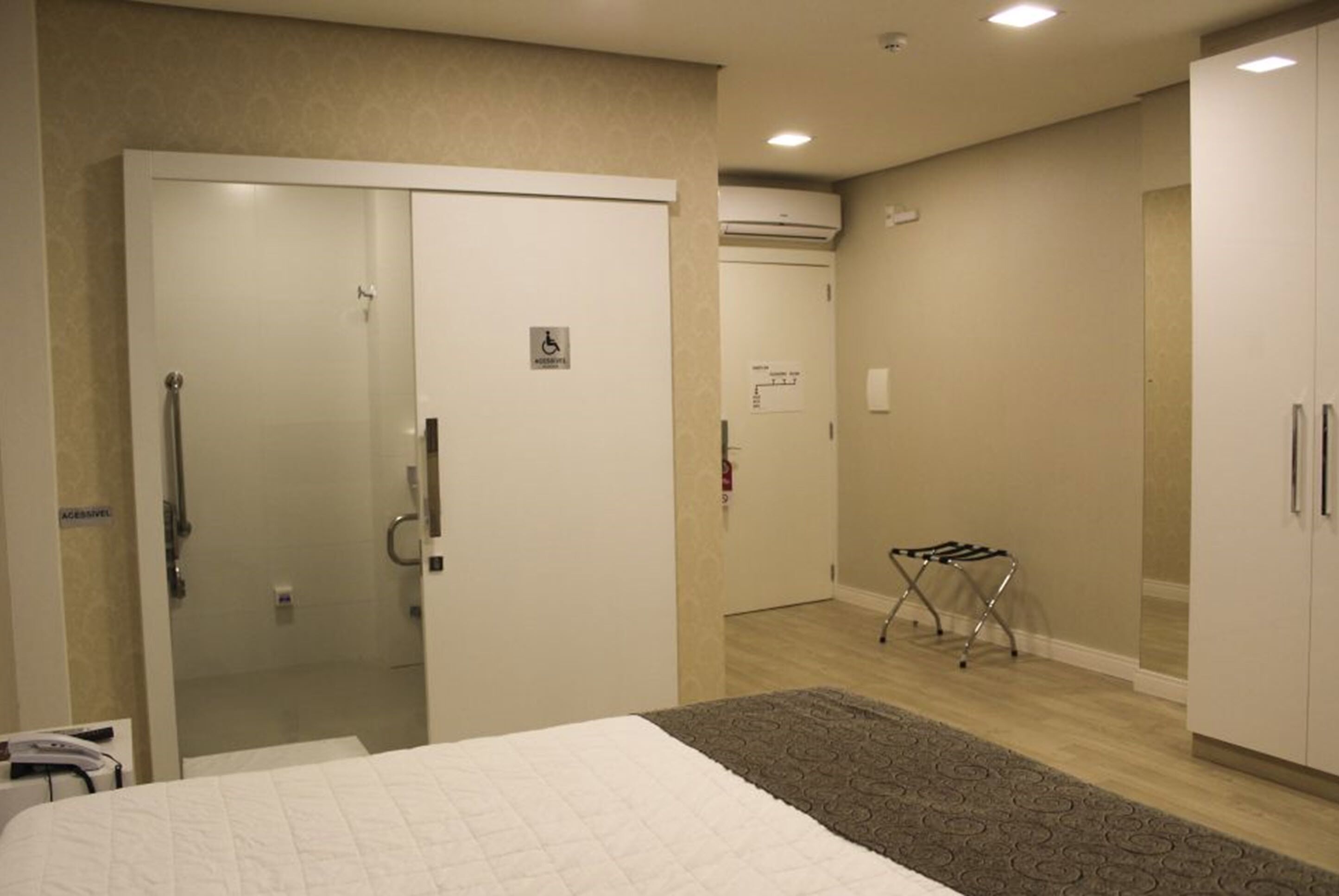 Habitación de hotel con cama, armario, zona de ducha y un tendedero.