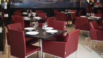 A restaurant with tables set for dining, red chairs, and a cityscape mural on the wall.