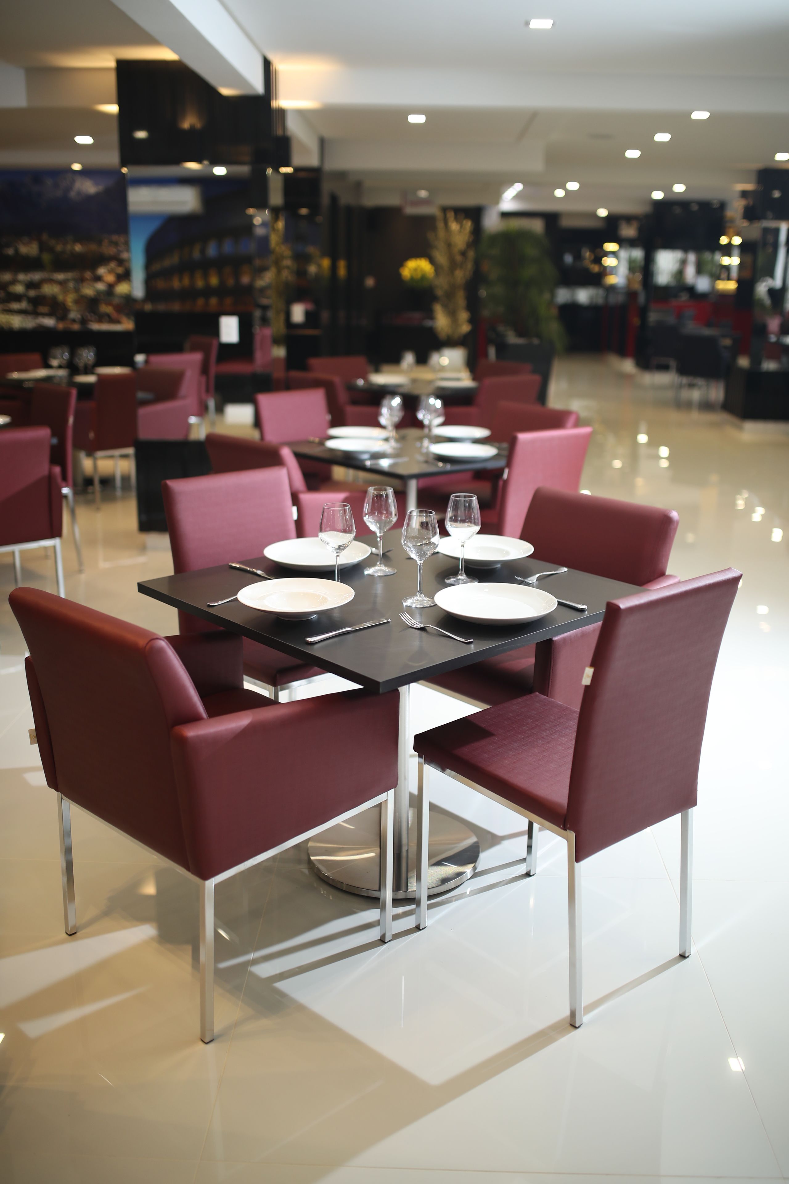 A restaurant with tables set for dining, featuring modern chairs and a polished floor.
