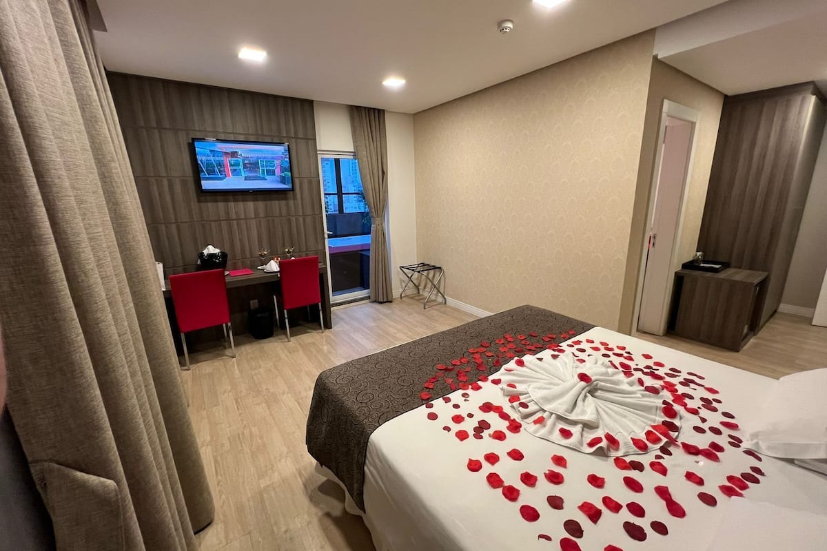 Ein Hotelzimmer mit Bett, Schreibtisch, Fernseher und Blick auf die Stadt.