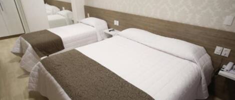 A hotel room with two beds, a wooden headboard, a patterned carpet, and a white wall with a subtle design.