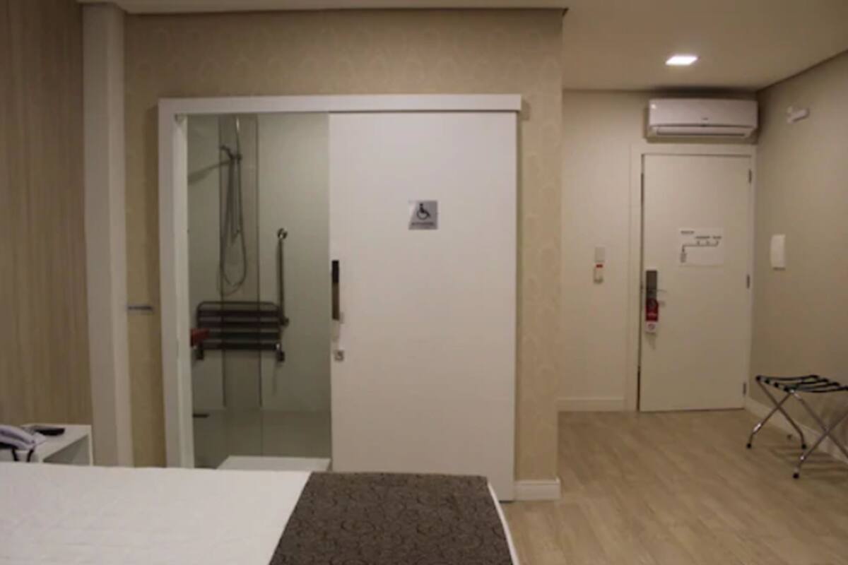 Ein Hotelzimmer mit Bett, Duschbereich und einer Tür mit Rollstuhlgerechterkeitsschild.