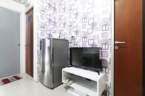 Une cuisine dotée d’un réfrigérateur en acier inoxydable, d’un téléviseur encastré dans un meuble blanc et d’un mur orné d’un motif.