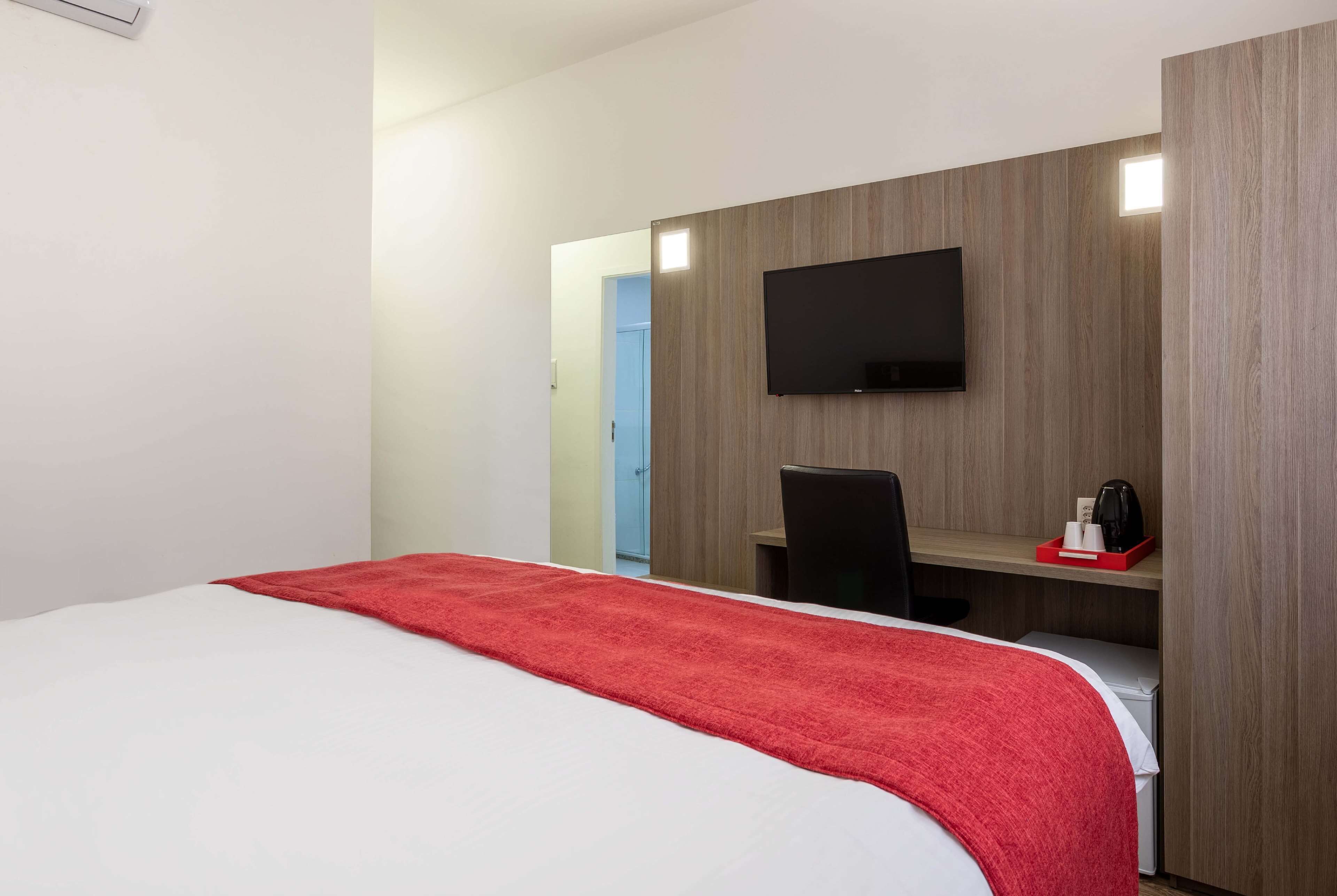 Une chambre d’hôtel équipée d’un lit, d’un bureau, d’une chaise, d’une télévision et d’un petit coin cuisine.