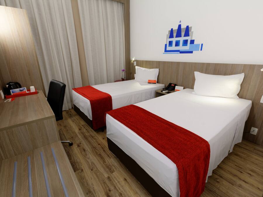 A hotel room with two beds, a desk, and a chair.