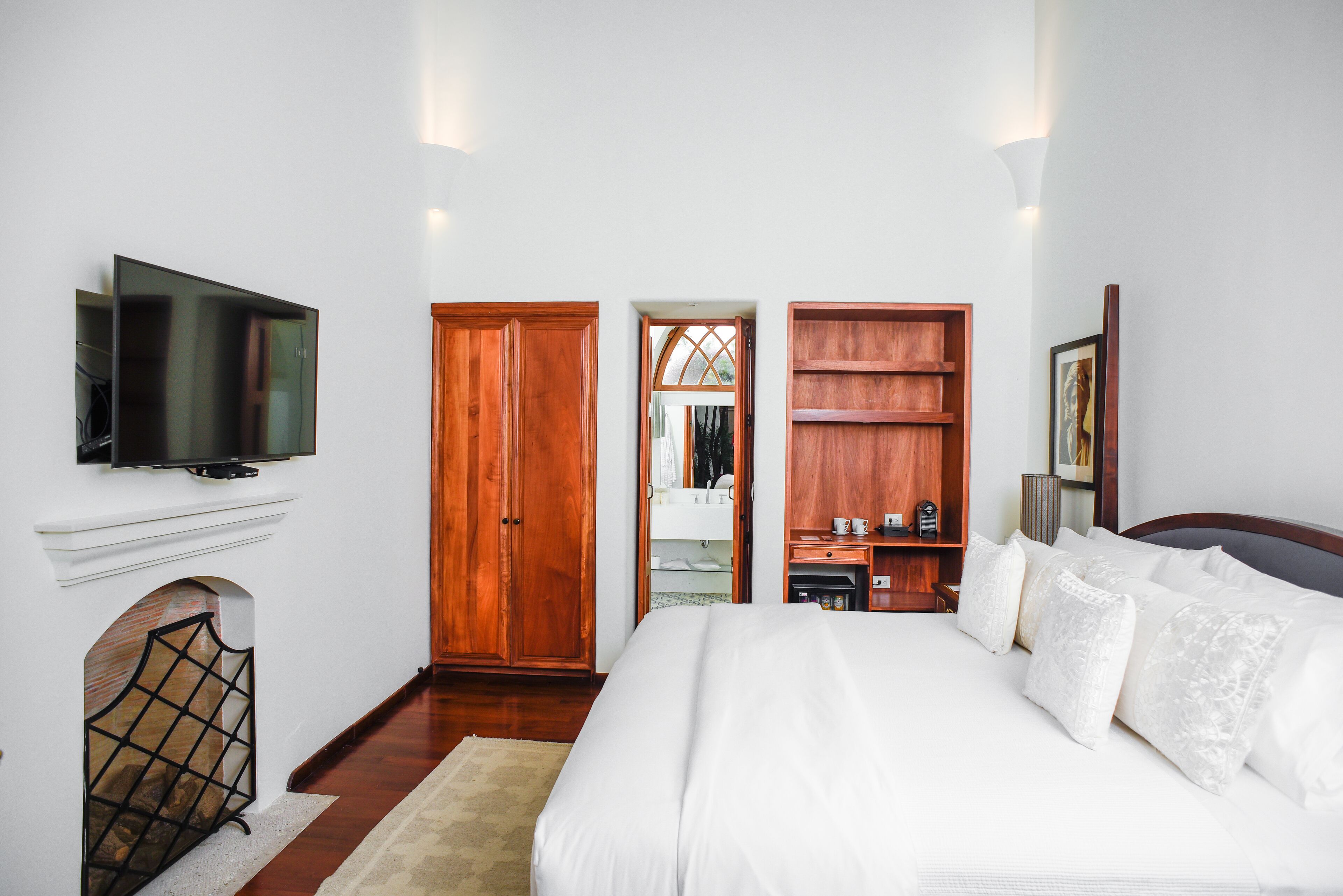 Un dormitorio con una cama grande, un armario de madera y un televisor instalado en la pared.