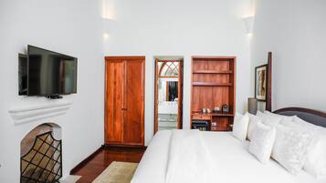 Un dormitorio con una cama grande, un armario de madera y un televisor instalado en la pared.