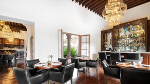 A restaurant with wooden floors, black leather chairs, and a bar area with a glass display of bottles. - Hotel Casa Blanca 7 (San Miguel de Allende)