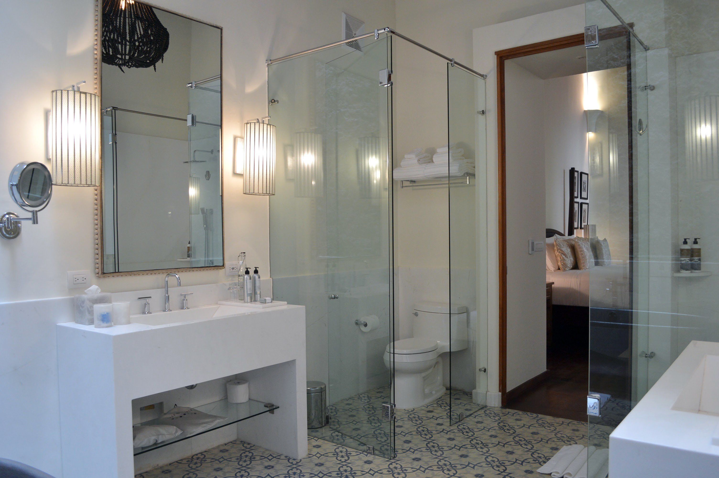A modern bathroom with a glass-enclosed shower, a large mirror, and a white sink.