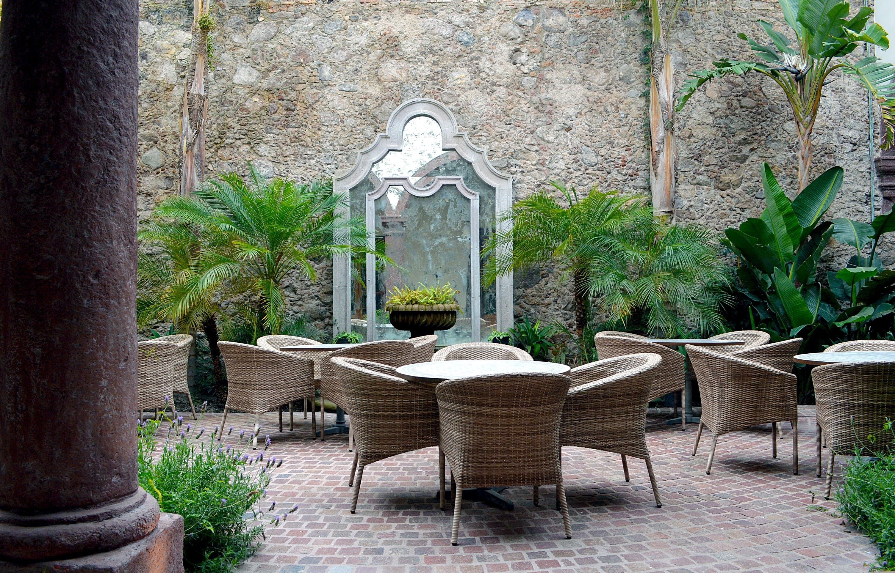 Un patio con mobiliario de mimbre y una pared de piedra.