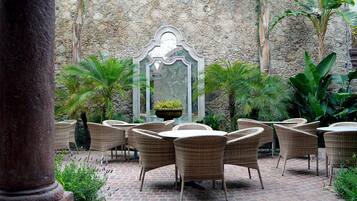 Un patio con mobiliario de mimbre y una pared de piedra.