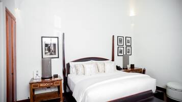 A neatly arranged hotel room with a large bed, bedside tables, a desk, and a chair.