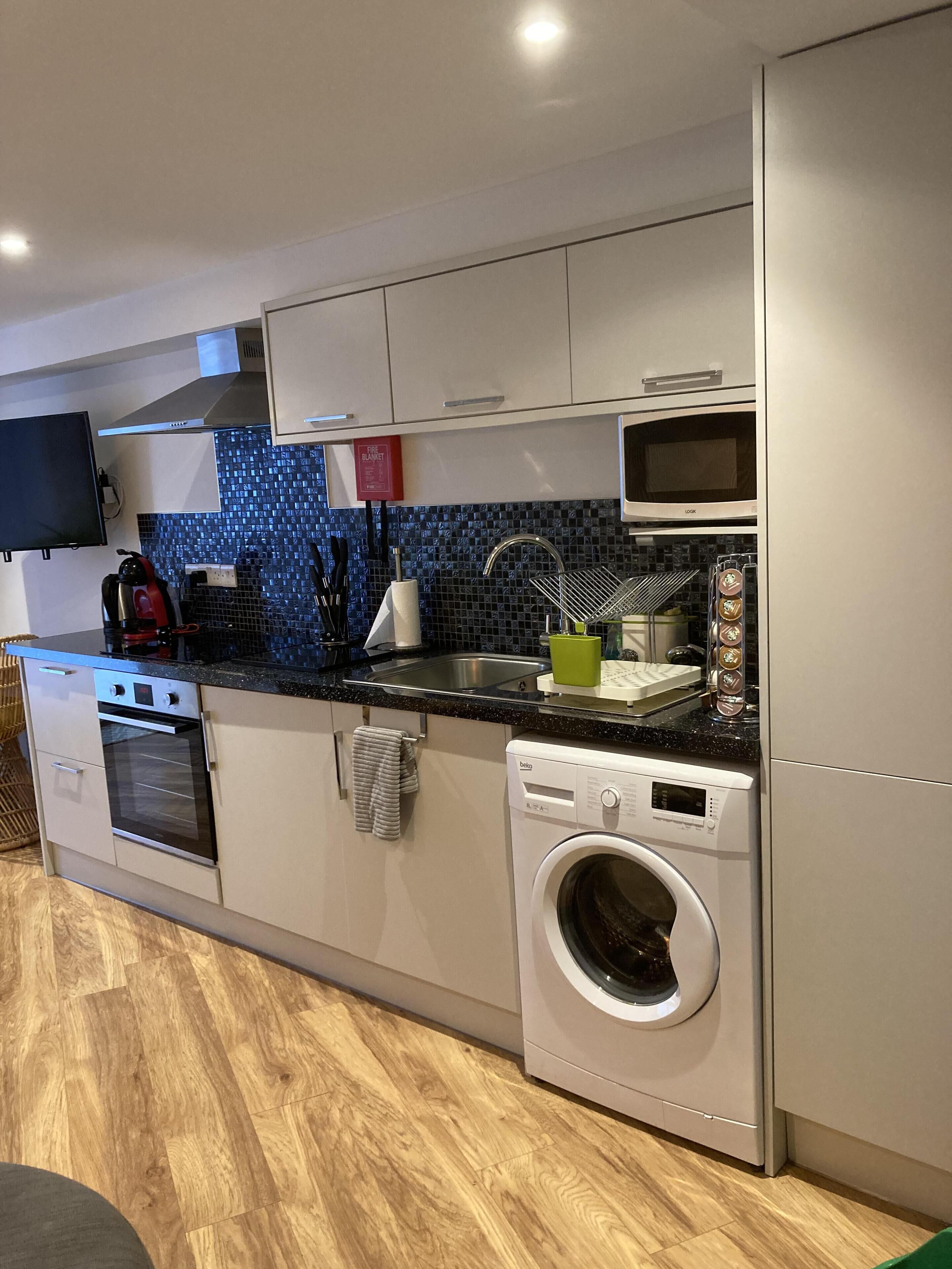 Een kleine keuken met een ingebouwde oven, magnetron en vaatwasser.
