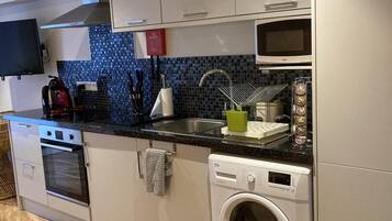 Een kleine keuken met een ingebouwde oven, magnetron en vaatwasser.