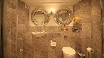 A modern bathroom with two large mirrors, a sink, a toilet, and a shower area.